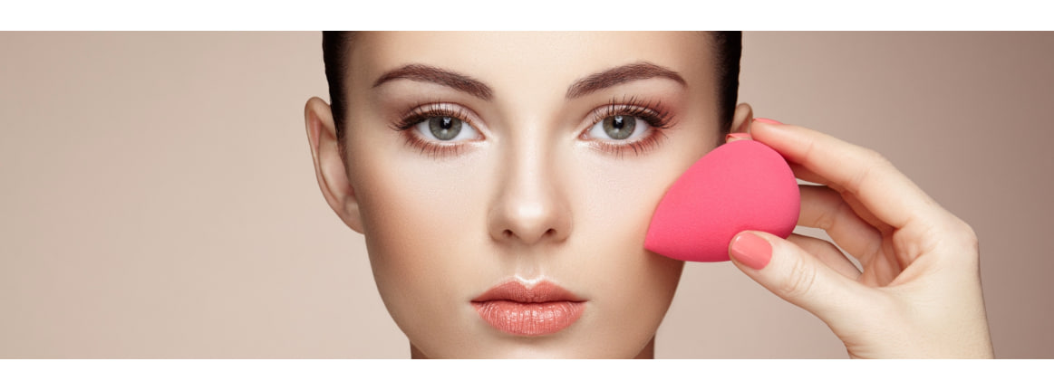 frau mit makelloser haut durch deckendes make up und make up schwämmchen in gesicht