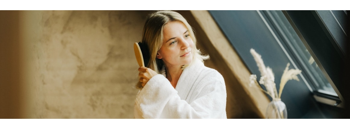 frau in bademantel kämmt sich die haare