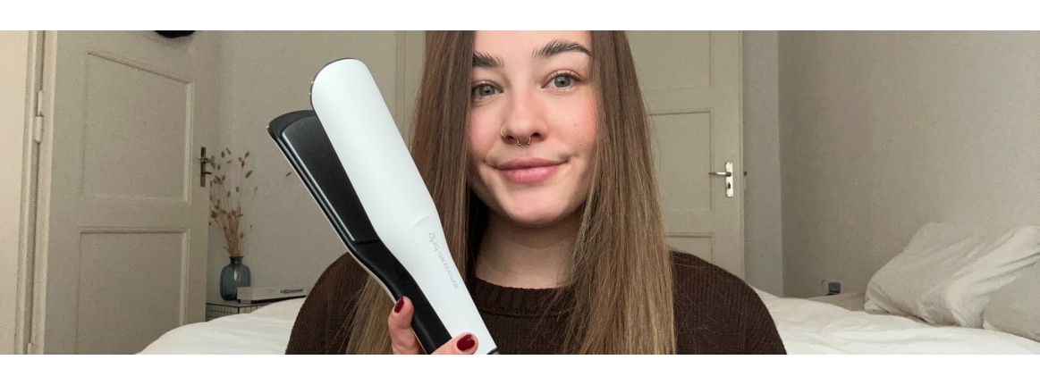 weisses haarglaetteisen ghd chronos max in der hand bei frau mit langem braunem haar