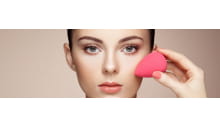 frau mit makelloser haut durch deckendes make up und make up schwämmchen in gesicht
