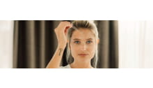 frau mit blondem haar tropft serum mit pipette auf die stirn