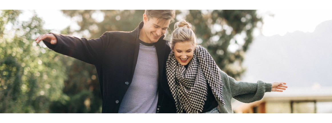 mann und frau im herbstlichen sonnenlicht schlendernd am see