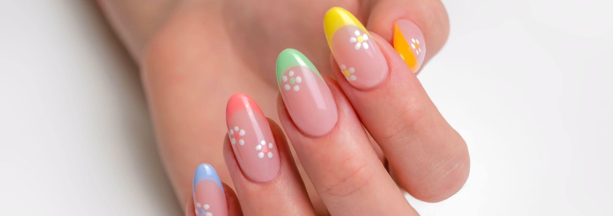 hand mit farbigen nagelspitzen und weissen blumen auf dem nagel